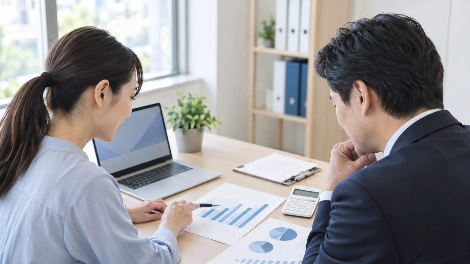 月次資料と電卓を使い経営状況を確認する担当者
